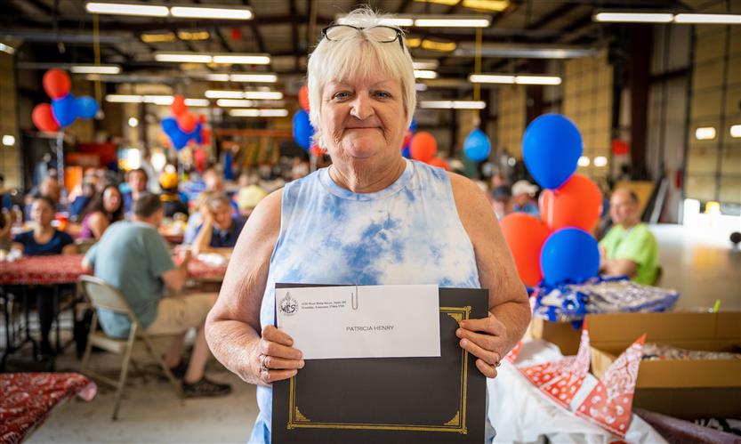 A woman holding a certificate smiles